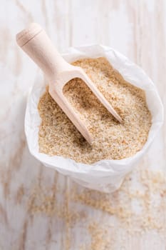 Heap of psyllium husk in small bag on wooden table table. Psyllium husk also called isabgol is fiber derived from the seeds of Plantago ovata plant found in India.