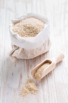 Heap of psyllium husk in small bag on wooden table table. Psyllium husk also called isabgol is fiber derived from the seeds of Plantago ovata plant found in India.