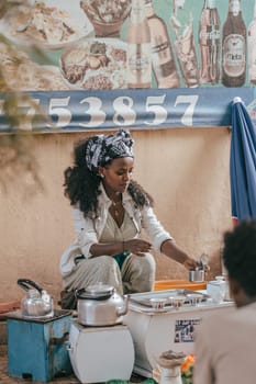 Aksum, Ethiopia - April 27, 2019: Ethiopian traditional Coffee maker, local women preparing bunna cafe behind Aksum KIdist Maryam Hospital, Ethiopia, Africa