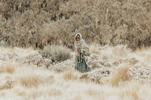 SIMIEN MOUNTAIN, ETHIOPIA, APRIL 25.2019, Little Ethiopian shepherdess girl veiled in a blanket with whip in cold morning. Chenek - Simien Mountains, Ethiopia, April 25. 2019