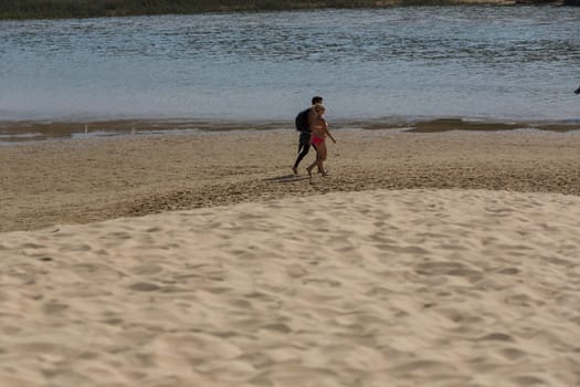 PRAIA DA BORDEIRA, PORTUGAL - AUGUST 20, 2017: People at the dunes of the famous beach of Praia da Bordeira. This beach is a part of famous tourist region of Algarve.