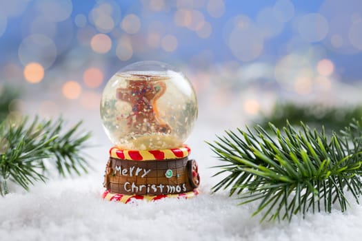 Snowball with branch on snow with blurry background. Symbol of winter and Christmas.