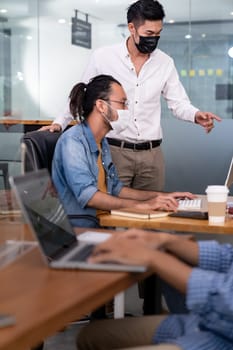 Group of interracial business worker team wear protective face mask in new normal office with social distance practice with hand sanitiser alcohol gel on table prevent coronavirus COVID-19 spreading