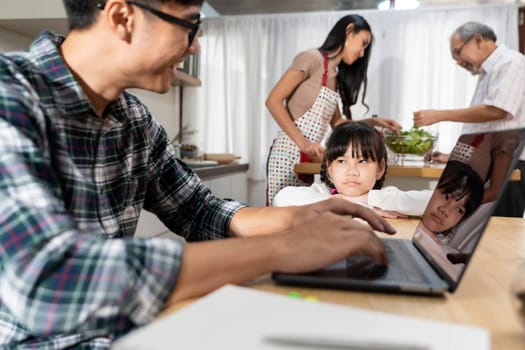 Asian upset girl looking and waiting her father working from home while city lockdown in dining room while mom and grandfather cooking in kitchen. Domestic life multigenerational family concept.