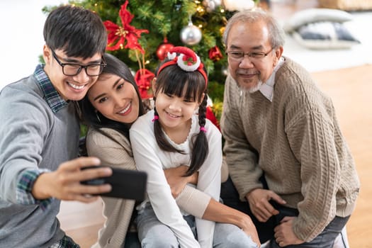 Multigenerational asian Family ,Mom Dad daughter girl and grandfather ,selfie with a Christmas tree after decorate the Christmas ornament prepare season greeting of Merry Christmas and Happy Holidays.