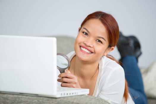 young beautiful woman sitting on sofa with laptop at home