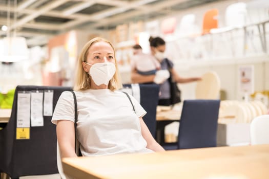 New normal during covid epidemic. Caucasian woman shopping at retail furniture and home accessories store wearing protective medical face mask to prevent spreading of corona virus.