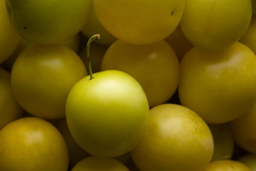 4 - Top lit large selection of yellow mirabelle plums. Home grown local produce, ripe and ready to eat. Stalk still present in the subject plum.