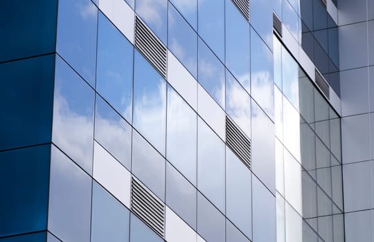 The ventilation grids, exterior facade of a building covered with glass reflections of the clouds taken. ventilation grills to be emphasized in this photograph and the glass-clad building on the original.