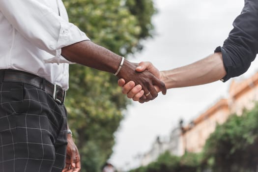 Handshake between african and a caucasian man outdoors.