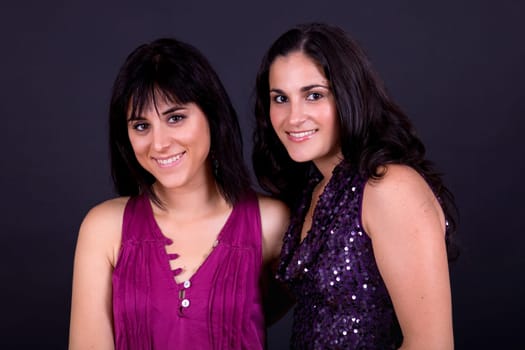 two happy young casual women on a black background