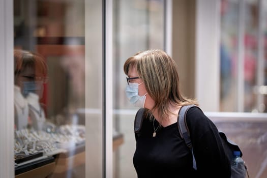 Woman goes window-shopping with a protective mask because of existing mask requirement