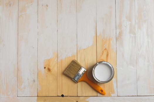 Paintbrush and can lying on partially painted wooden background. Top view. Copyspace