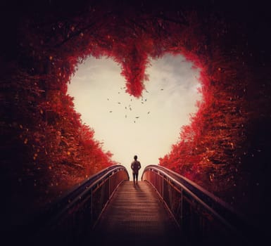 Follow your heart concept. A lone person lost in the autumn forest, found the way out of the woods, as walks a path through the heart shaped trees. Surreal and magic scene, red fall colors.