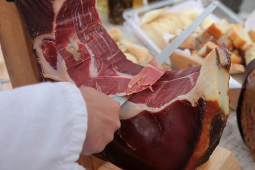 A hand cutting prosciutto
