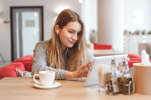 Young gorgeous woman wathing video online at the cafe