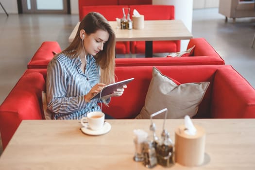 Candid image of a young woman using tablet computer in a cafe