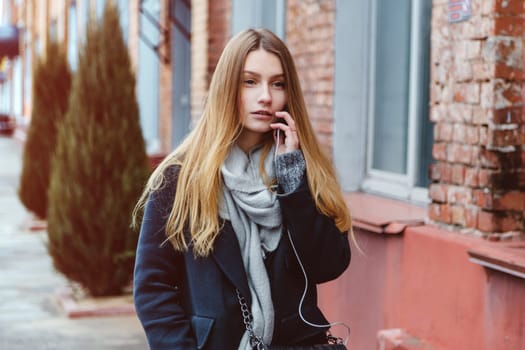 Girl walking on the street uses a smart phone