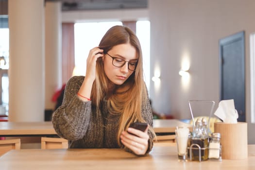 Stylish attractive young businesswoman sitting at the table in the cafe