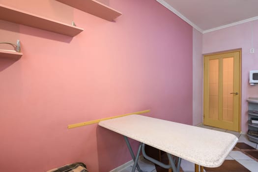 Fragment of kitchen interior, dining table and part of a painted wall with shelves