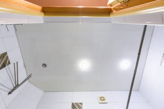 A fragment of a bathroom interior, a view of the ceiling made of plastic panels with three lamps, one light bulb burned out