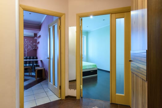 Layout of a one-room apartment, view from the hallway to open doors to the kitchen and a room in a one-room apartment