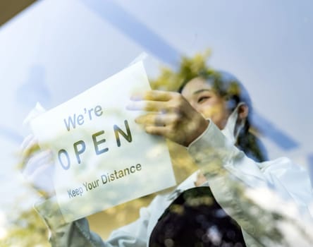 Focus on restaurant signage. Asian female waitress putting on open signage with social distance for new normal restaurant. New normal restaurant lifestyle concept.