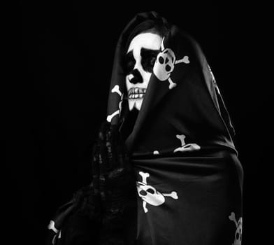 woman with skeleton make-up stands in prayer pose, wearing black silk cloak cape, black background