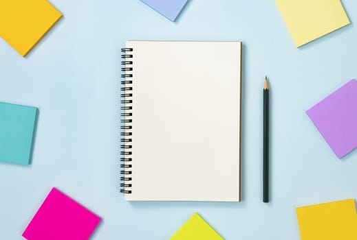 Spiral Notebook or Spring Notebook in Unlined Type and Multi Color Sticky Note and Pencil on Blue Pastel Minimalist Background. Spiral Notebook Mockup on Center Frame