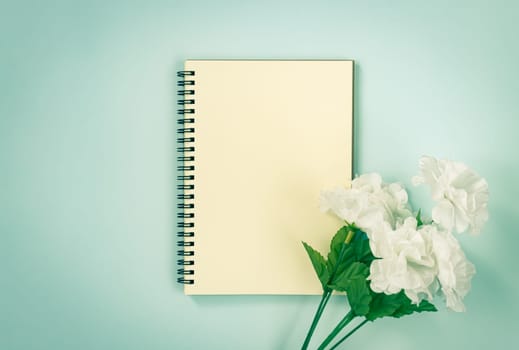 Spiral Notebook or Spring Notebook in Unlined Type and White Flowers at Bottom Right on Blue Pastel Minimalist Background in Vintage Tone