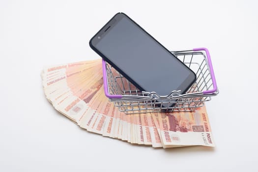 Against the background of five thousandth bills, there is a grocery basket in which the phone lies