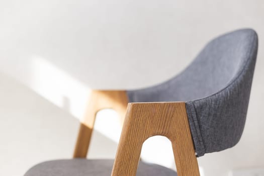 Contemporary modern kitchen armchair with wooden furniture legs. Close up view with soft focus.