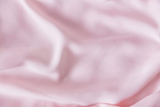 Pink wrinkled silk fabric. The pink fabric is laid out waves. Pink fabric background or texture