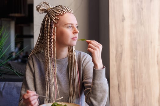 Portrait of caucasian hipster vegan woman eating in restaurant.