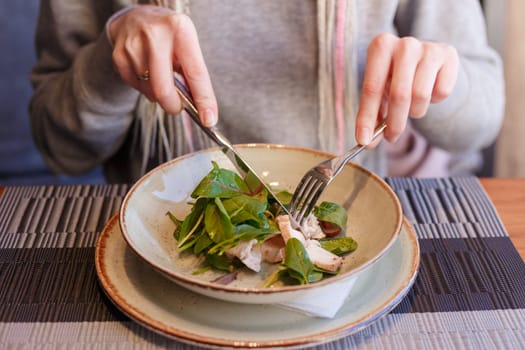 healthy eating, dieting and people concept - close up of young woman hands eating salad in cafe.