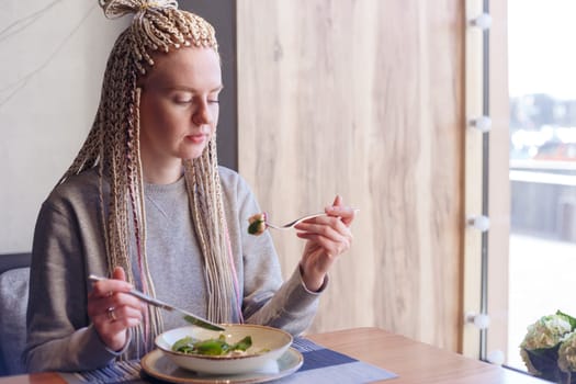 Young attractive woman sitting in a cafe with a salad.