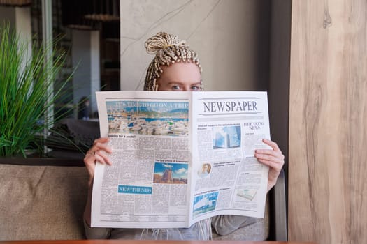Woman sitting in cafe reading news hiding behind a newspaper.