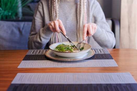Healthy eating, dieting and people concept - close up of young woman hands eating salad in cafe