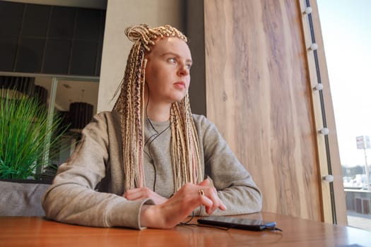 Worried young hipster woman in cafe. Lateness or punctuality concept.