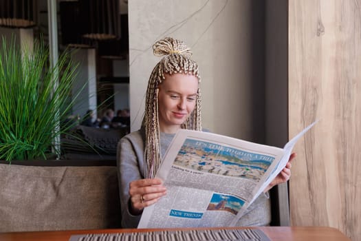 Attractive young business woman reading a newspaper at cafe.