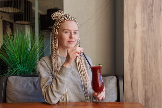 Young hipster woman kanekalons drinking berry cocktail smoothie with a straw.