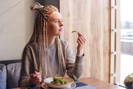 healthy eating, dieting and people concept - close up of young woman hands eating salad in cafe.