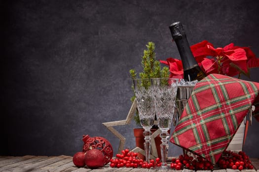 Champagne bottle in bucket with ice, empty champagne flutes and Christmas ornament on dark background with copy space. Christmas. New Year. Design element for greeting card, invitation, advertising