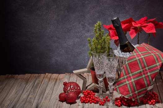Champagne bottle in bucket with ice, empty champagne flutes and Christmas ornament on dark background with copy space. Christmas. New Year. Design element for greeting card, invitation, advertising