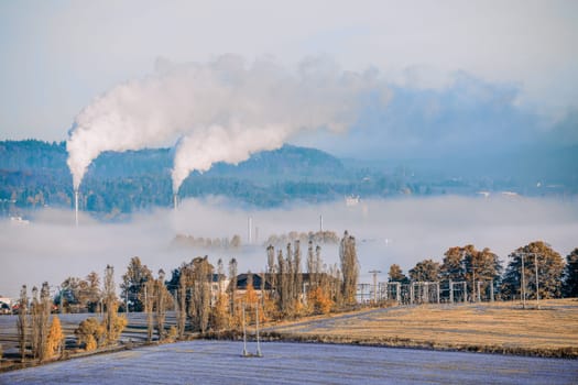 industrial cityscape with with smoking factory, ecology and pollution concept. Autumn fall season with mist. Jihlava Kronospan, Czech Republic