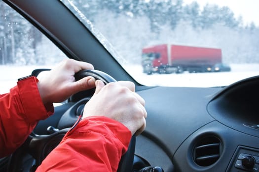 Driving in snowfall with man hands on a steering wheel