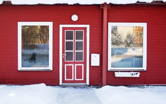 Red door in wintertime with snow on the foreground