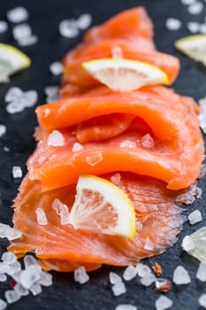 Smoked salmon with lemon and sea salt on black background. Healthy food concept.