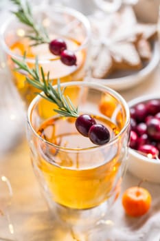 Christmas apple cider cocktail with cranberries, rosemary and gingerbread cookies. Mulled apple wine for Christmas.