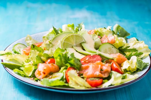 Healthy salad with smoked samlmon and avocado on cyan vackground
